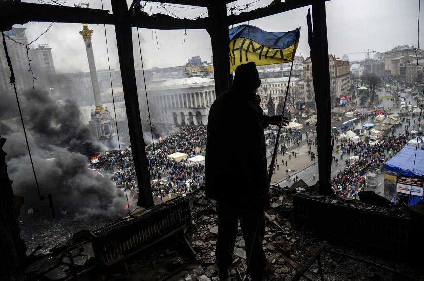 A protester holds an Ukranian national flag from a burned building during a face-off against police on February 20, 2014 in Kiev. Ukraine's embattled leader announced a "truce" with the opposition as he prepared to get grilled by visiting EU diplomats over clashes that killed 26 and left the government facing diplomatic isolation. The shocking scale of the violence three months into the crisis brought expressions of grave concern from the West and condemnation of an "attempted coup" by the Kremlin. AFP PHOTO/BULENT KILICBULENT KILIC/AFP/Getty Images