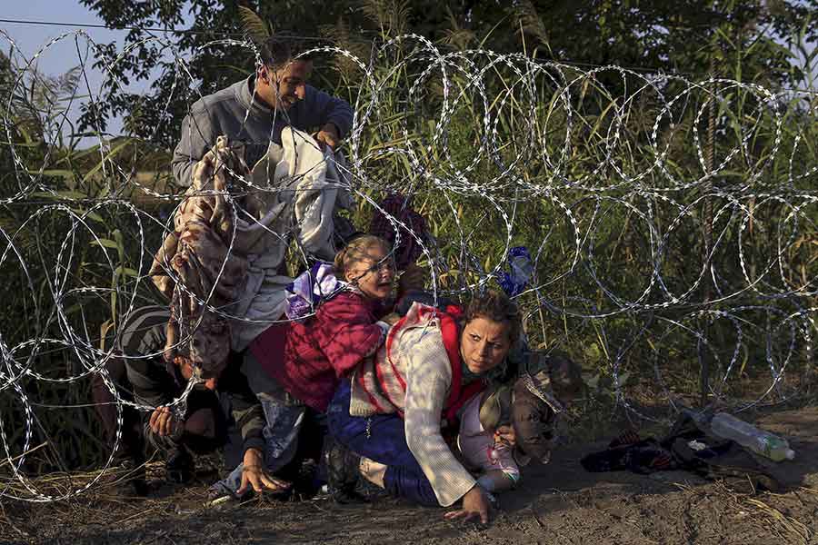 Syrian migrants cross under a fence as they enter Hungary at the border with Serbia / Bernadett Szabo, Thomson Reuters - August 27, 2015