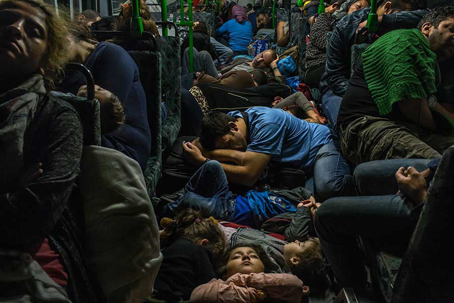 Ahmad Majid, in blue T-shirt at center, sleeps on a bus floor with his children, his brother Farid Majid, in green sweater at right, and other members of their family and dozens of other refugees, after leaving Budapest on the way to Vienna / Mauricio Lima, The New York Times - September 5, 2015