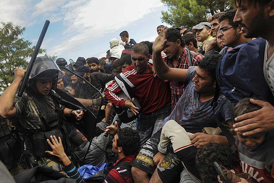 A Macedonian police officer raises his baton towards migrants to stop them from entering into Macedonia at Greece's border near the village of Idomeni / Alexandros Avramidis, Thomson Reuters - August 22, 2015