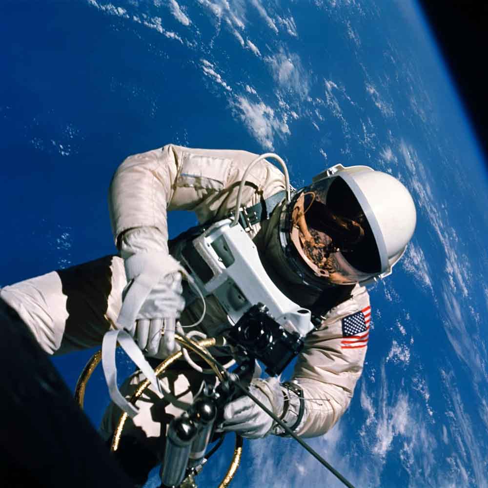ASTRONAUT EDWARD H. WHITE FLOATING IN ZERO GRAVITY WITH EARTH BEHIND HIM, JUNE 1965 © NASA