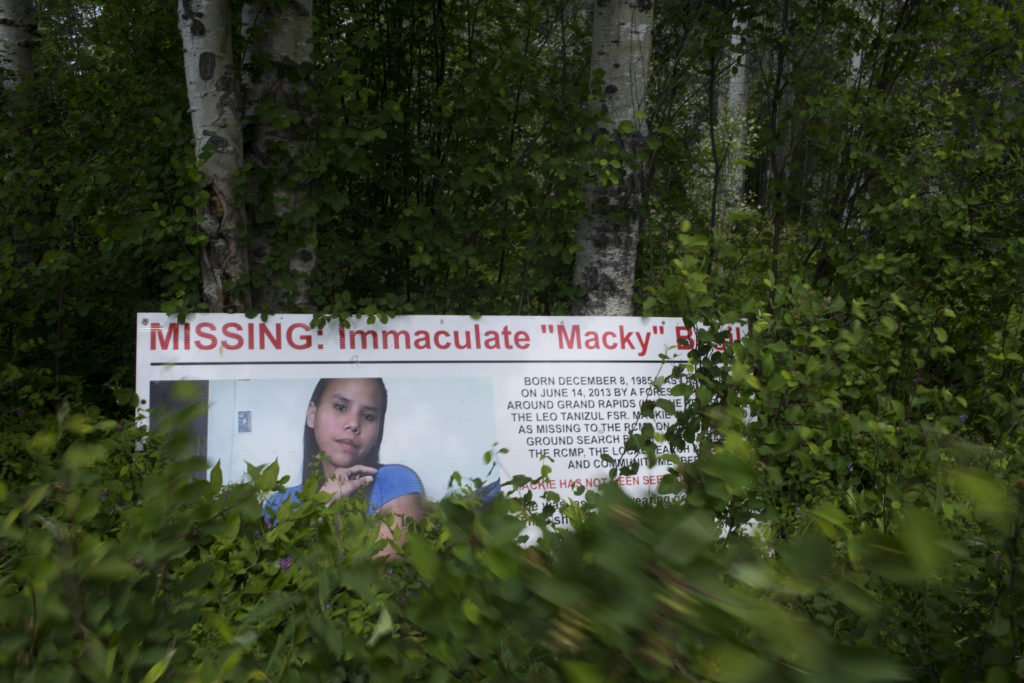 Progetto Searching for Mackie .  Un cartellone dedicato alla scomparsa di Macky Basil all’ingresso del villaggio di Tachie. La gente continua a cercarla, ma non è facile nella vasta foresta della Columbia Britannica settentrionale. 