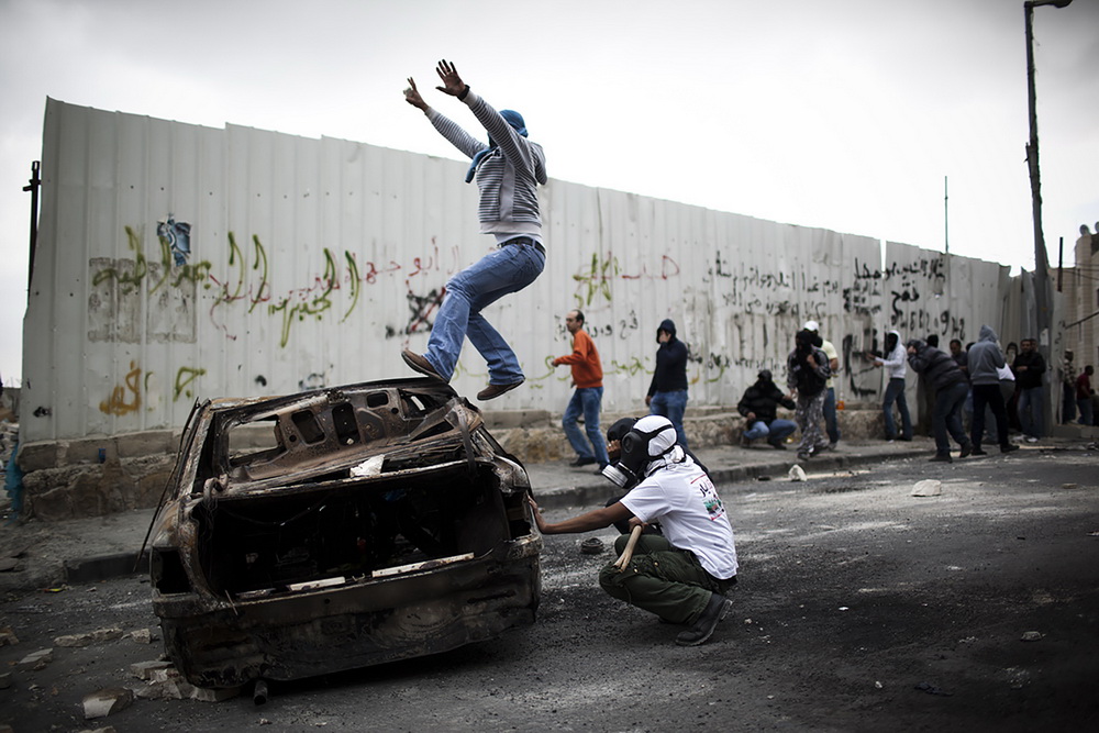 Il palestinese salta su un'auto durante gli scontri con la polizia israeliana