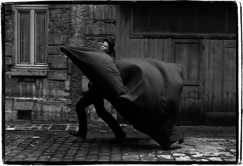 Tom Waits che corre per un cortile avvolto in un mantello ricavato dal fondale di un altro fotografo. Harari,