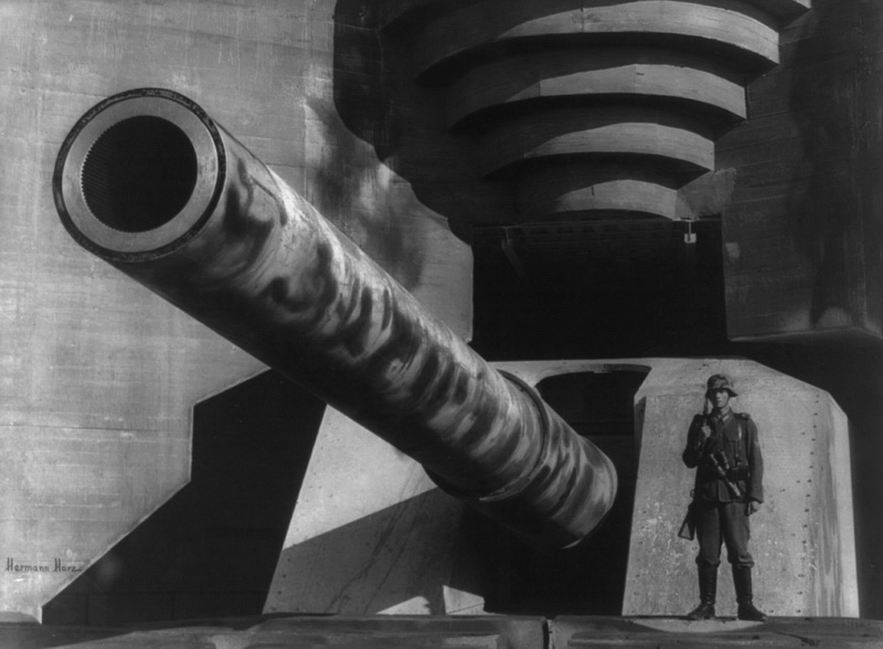 “Barrel of a large gun with German soldier at fortification”. The photo is from 1943 but it is against fortifications like these that the Allied invasion force is going to clash during the battle of Normandy.  1943 Normandy, France Photographer: Hermann Harz Courtesy Library of Congress 