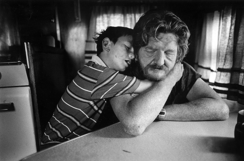 1985. Ventura, California, USA: Charlie abbracciato dal figlio. La famiglia è senza fissa dimora da due anni e vive in una roulotte sulla spiaggia del McGrath State Park.  © Stephen Shames