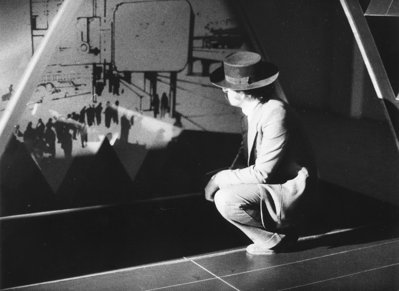 Questa immagine ritrae un momento del progetto "La Casa Telematica", un'installazione d'avanguardia presentata dall'architetto - artista alla Fiera di Milano nel 1983. L'opera, realizzata in collaborazione con Gianfranco Bettetini e Aldo Grasso, esplorava l'impatto delle nuove tecnologie di comunicazione (la "telematica") sullo spazio domestico e sulla vita quotidiana.