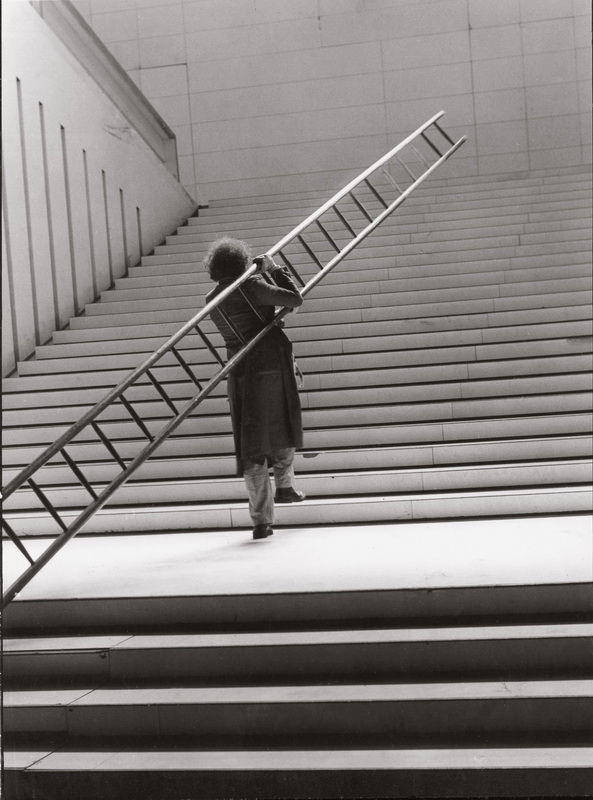 L'immagine ritrae un fotogramma del film d'artista "La grande occasione", realizzato da Ugo La Pietra nel 1973. L’opera, girata in bianconero all'interno del Palazzo dell'Arte (sede della Triennale di Milano), esplora la tensione e le contraddizioni dell'operatore culturale di fronte alle istituzioni.