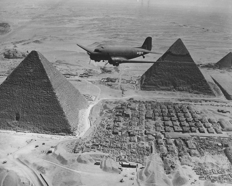 Un aereo dell’Air Transport Command sorvola le piramidi in Egitto; carico di rifornimenti e materiali di guerra urgenti, l’aereo fa parte di una flotta che li trasporta dagli Stati Uniti attraverso l’Atlantico e il Continente africano verso le zone di battaglia strategiche. Uomini e mezzi vengono concentrati in Nord Africa per partire alla conquista (leggi liberazione) del Continente europeo. La prossima operazione in programma è lo sbarco in Sicilia. E poi chissà, magari si riesce a liberare tutta l’Italia se le cose vanno nel verso giusto e si trova un accordo tra Downing Street e la Casa Bianca 1943, Egitto Autore sconosciuto o non fornito © Courtesy Collection National Archives at College Park / U.S. National Archives