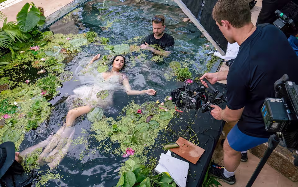 Padma Lakshmi immersa in una vasca piena d'acqua con fiori di loto che ne decorano la superficie: Padma Lakshmi, nata in India e naturalizzata statunitense è modella, attrice e conduttrice televisiva,   Backstage del Calendario Pirelli 2027 - PH Alessandro Scotti, Courtesy