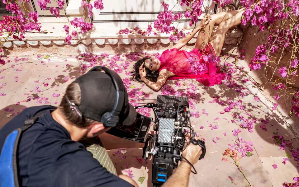 Freida Pinto, la star del cult The Billionaire del 2008, posa tra i fiori in uno scatto in cui dominano le tonalità ciclamino. Pinto, attrice di Mumbai classe 1984, ha recitato a Hollywood per Ron Howard, Woody Allen e Julian Schnabel. Backstage del Calendario Pirelli 2027 - PH Alessandro Scotti, Courtesy